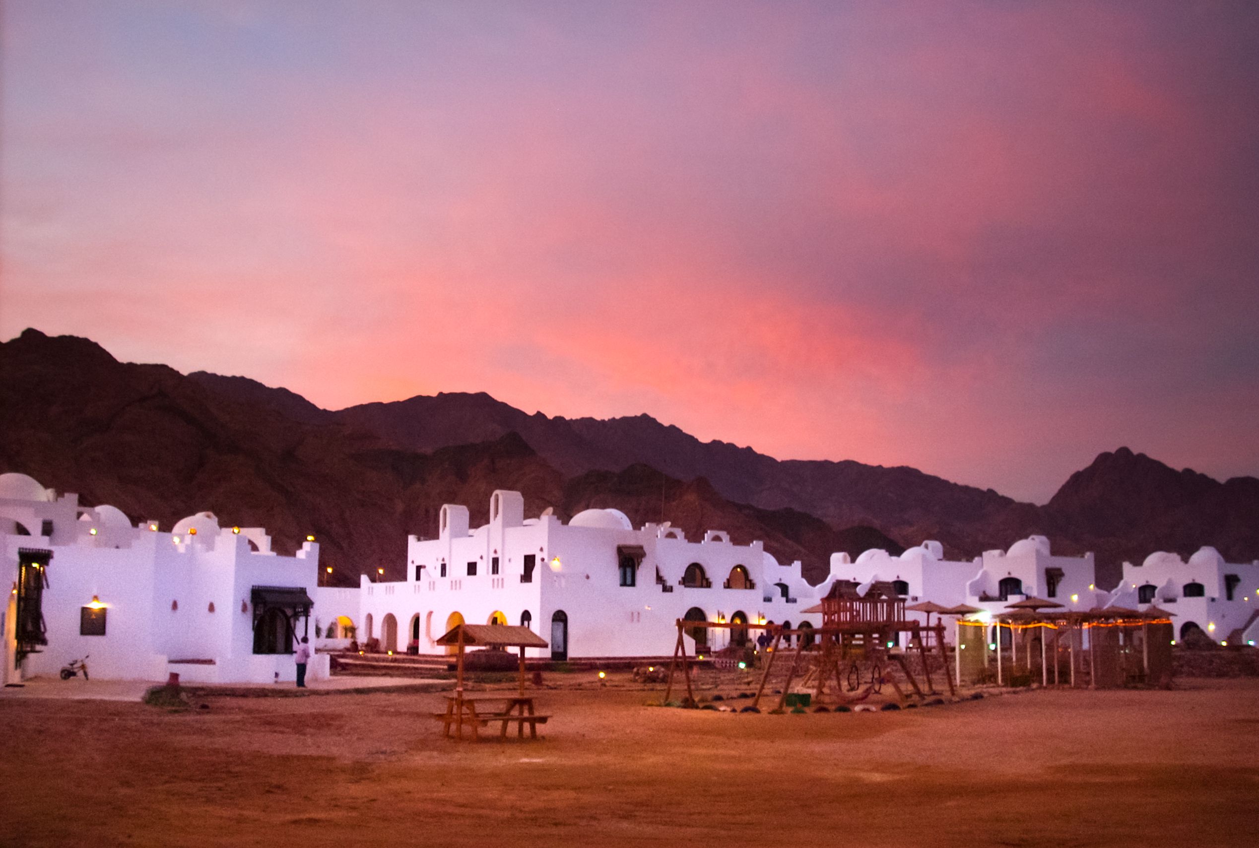 Stunning sunset over a traditional resort set against desert mountains.