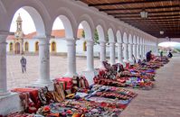 Vibrant display of handmade goods at the traditional market in Sucre, Bolivia under historic colonnades.