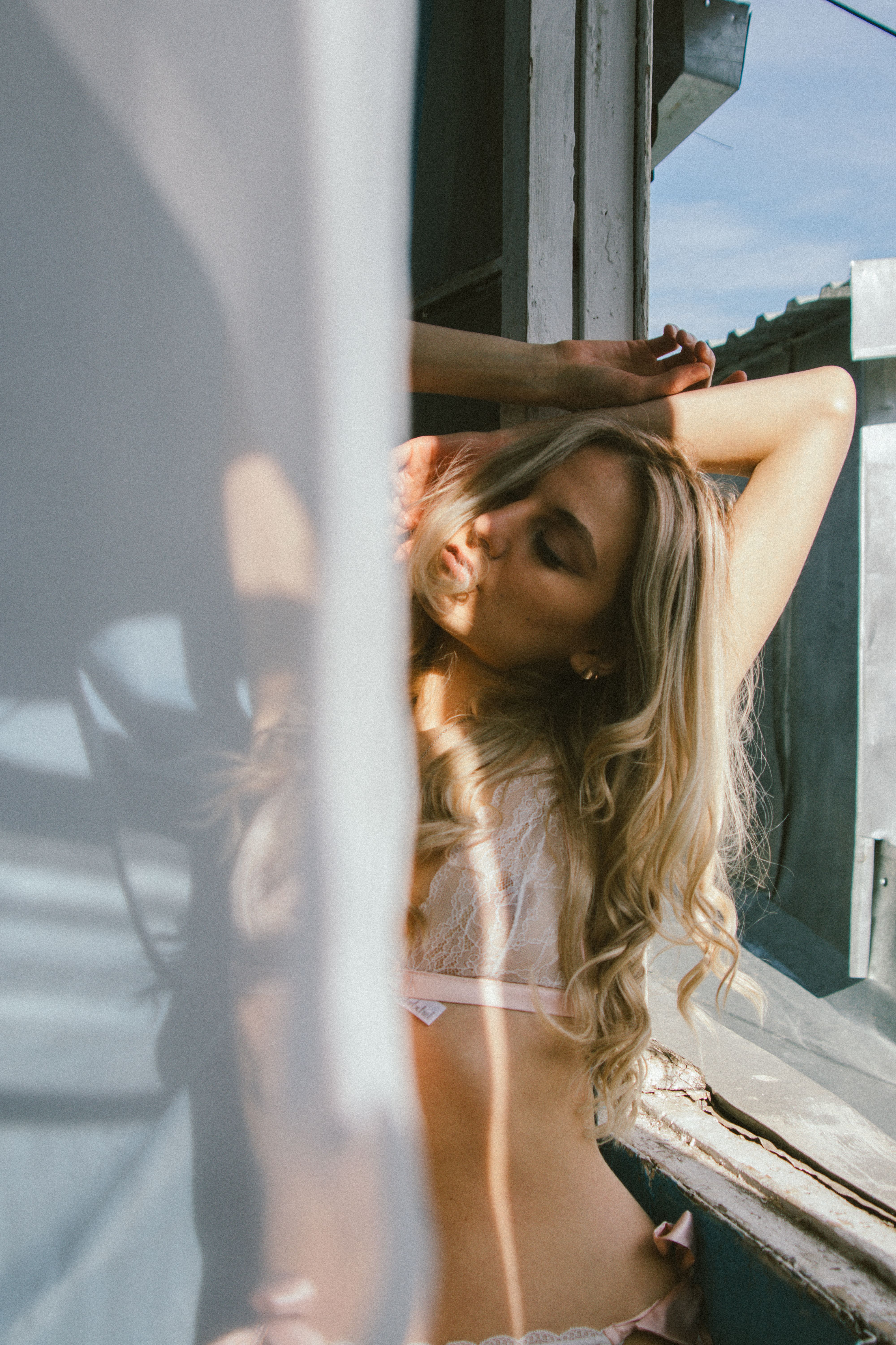A beautiful caucasian woman posing gracefully by a sunlit window indoors.