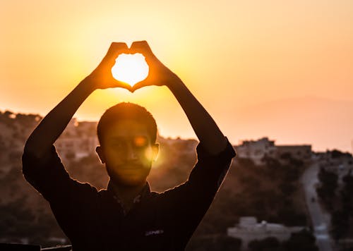 Person, Die Herzform Mit Seiner Hand Während Des Sonnenuntergangs Macht