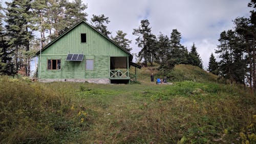 Green Wooden House on Green Grass Field Under White Clouds