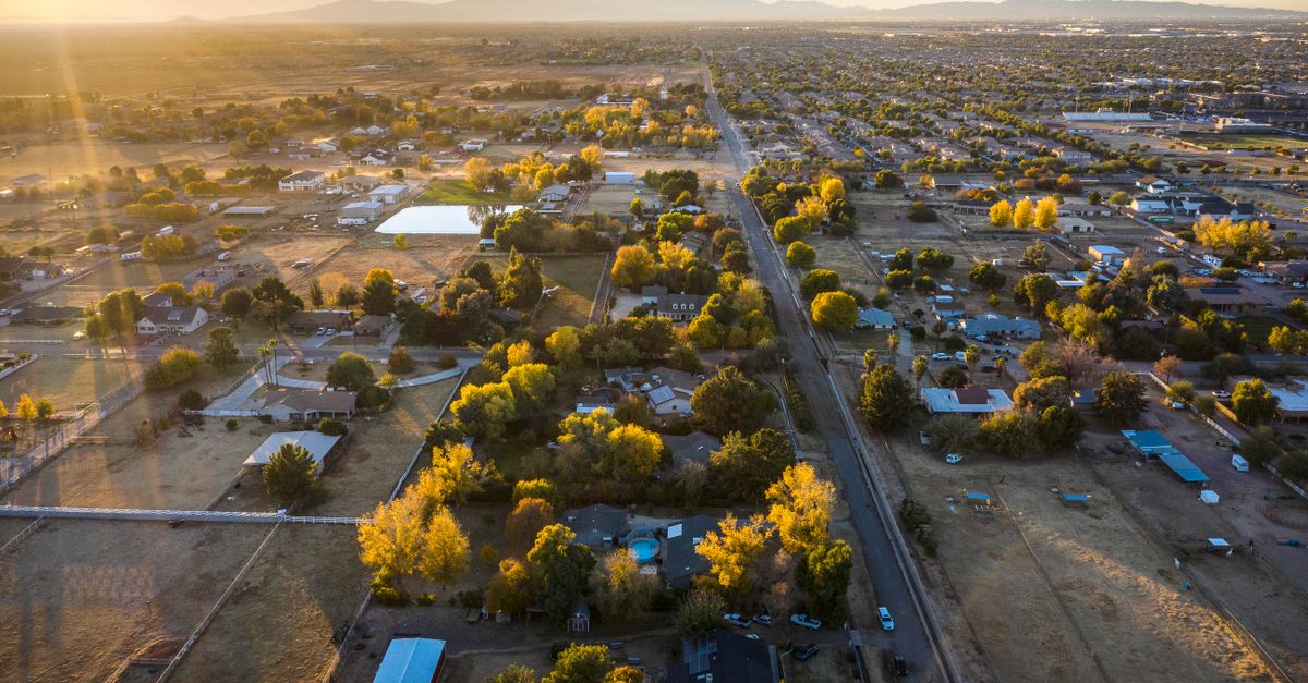 Drone shot capturing a serene rural landscape during a golden sunset, showcasing autumn colors.