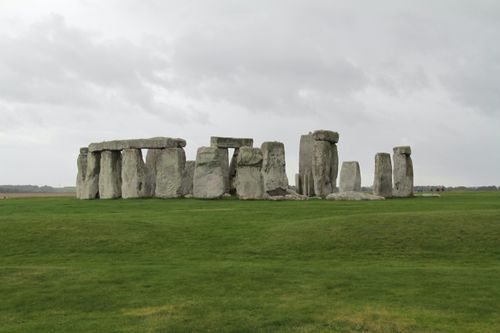 Free Capture of iconic Stonehenge stone circle under a dramatic cloudy sky, set in the green English countryside. Stock Photo