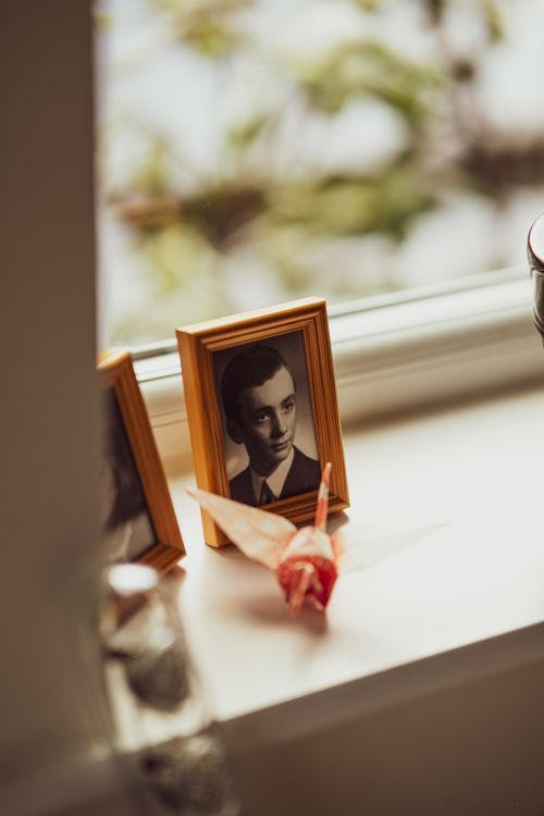 Free A vintage black and white portrait in a wooden frame on a windowsill, accompanied by colorful origami. Stock Photo
