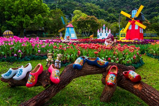 Vibrant tulip garden with decorative clogs and windmill in Taipei, Taiwan.