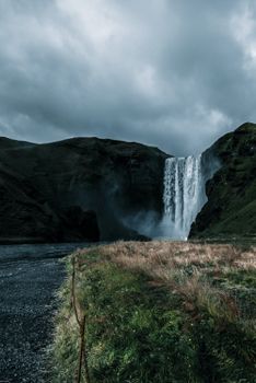 Discover a stunning Icelandic waterfall amidst dramatic rocky terrains and misty weather.