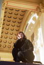 Woman in Black Coat Standing Near Brown Concrete Building