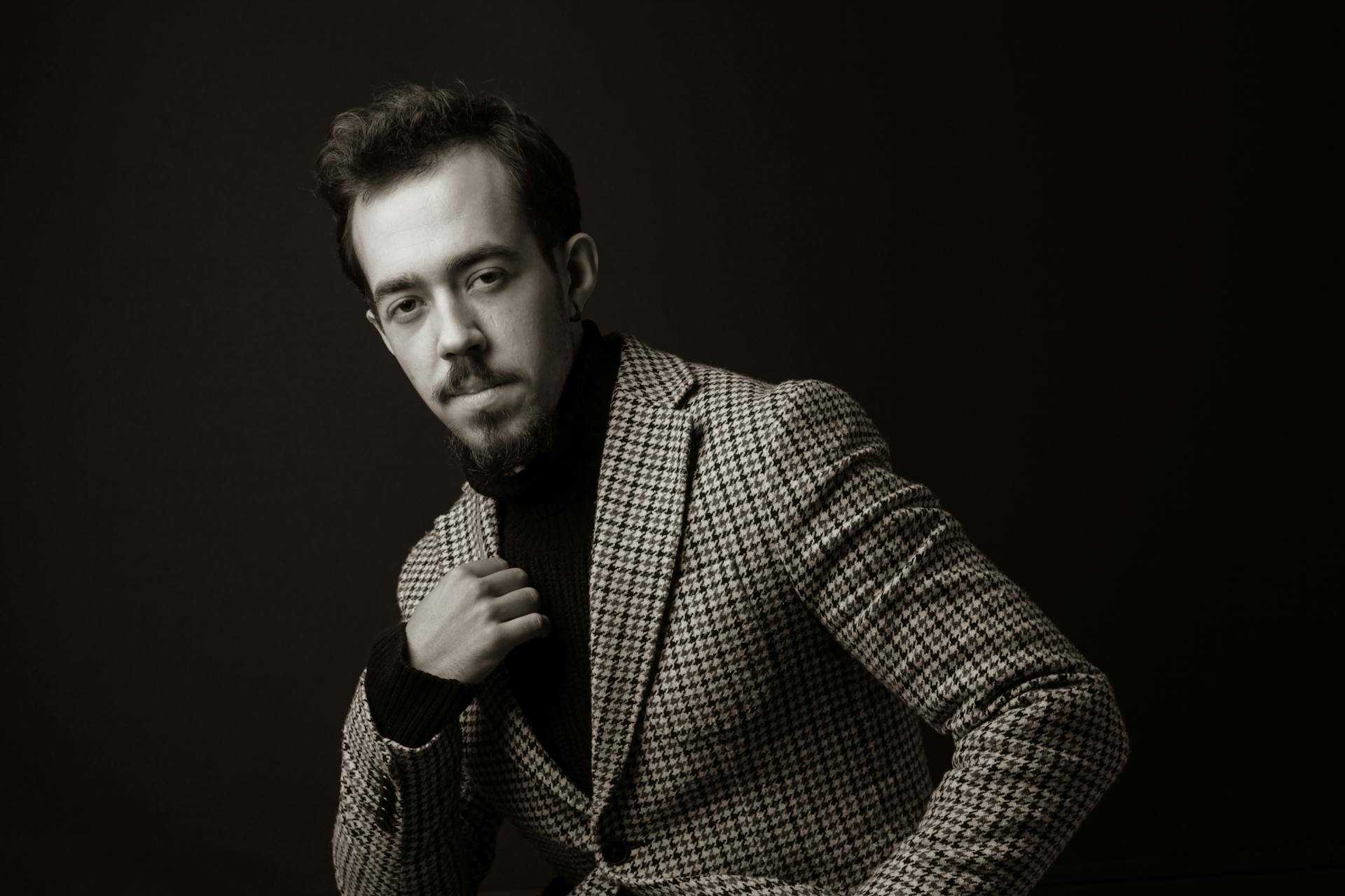 Stylish black and white portrait of a man in a plaid suit, exuding vintage elegance.