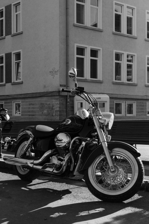 Free Classic black and white motorcycle parked on a city street, capturing urban elegance. Stock Photo