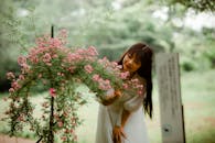 Woman in White Dress Beside the Pink Flower Plant