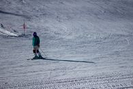 Person in Blue Jacket and Black Pants Riding on Ski Blades on Snow Covered Ground during