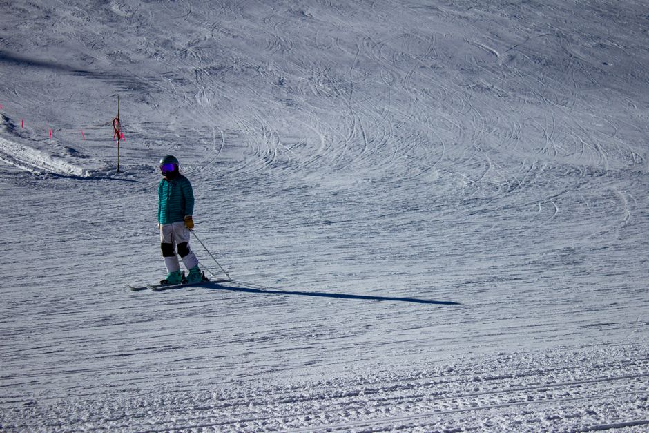 A skier in vibrant winter clothing glides down the snowy slopes at Winter Park, Colorado.
