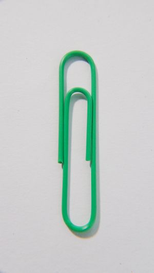 A single green paper clip on a white background, by Kindel Media on Pexels