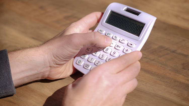 Photo Of A Person Using A White Calculator