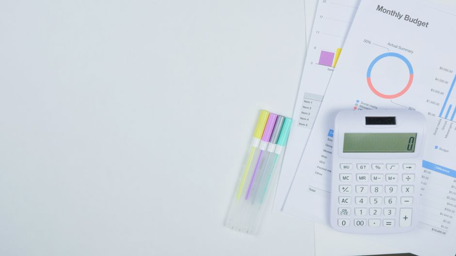 Calculator and financial spreadsheets on a desk showing budget planning numbers