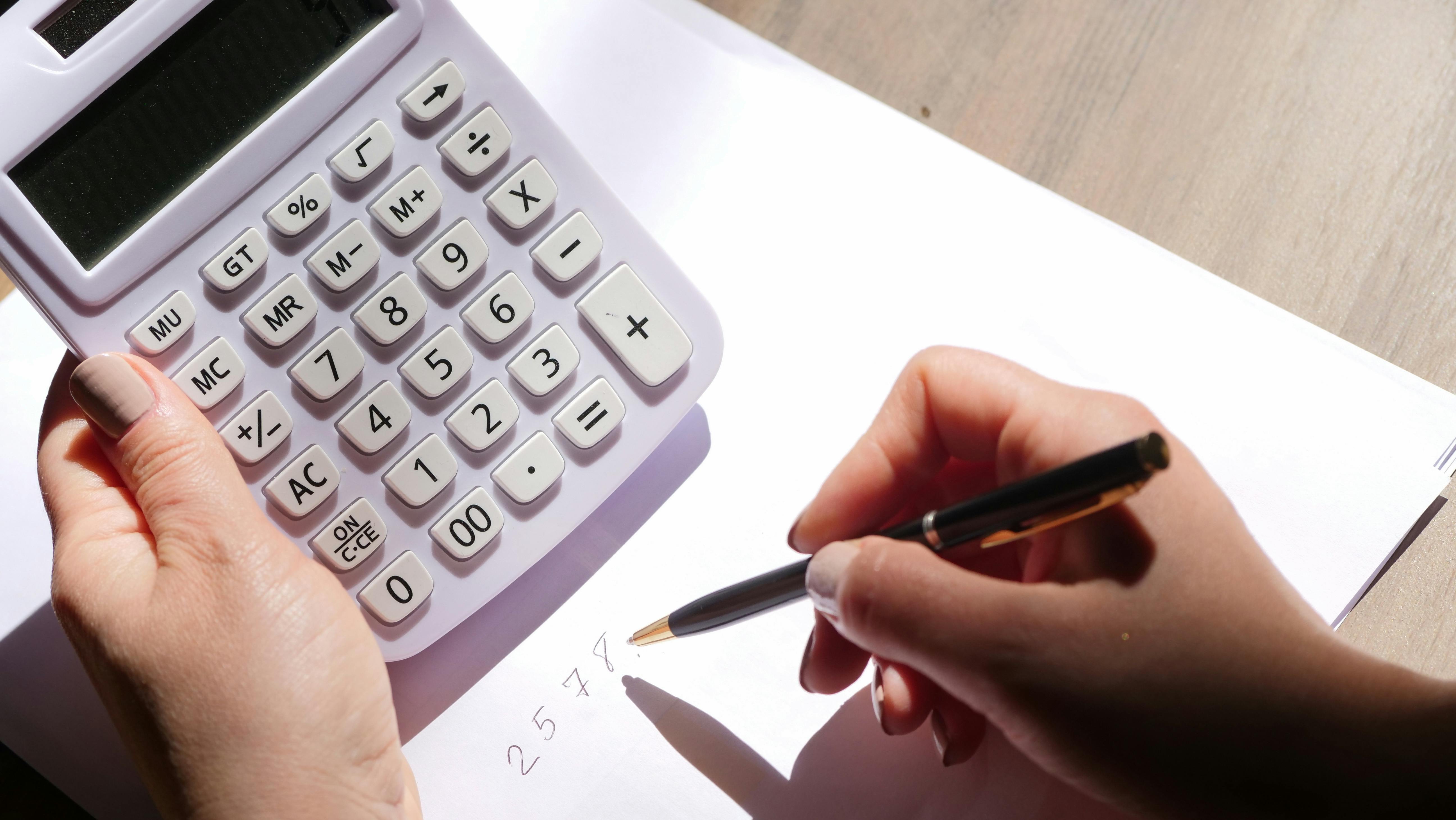 close up shot of a person holding a pen and a calculator