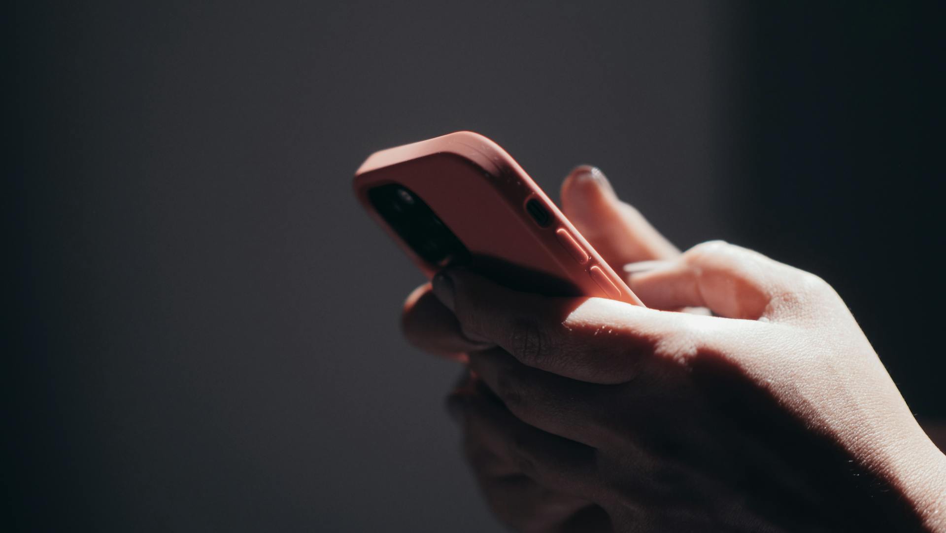 Close-Up Photo of a Person Using Cell Phone With Peach Phone Case