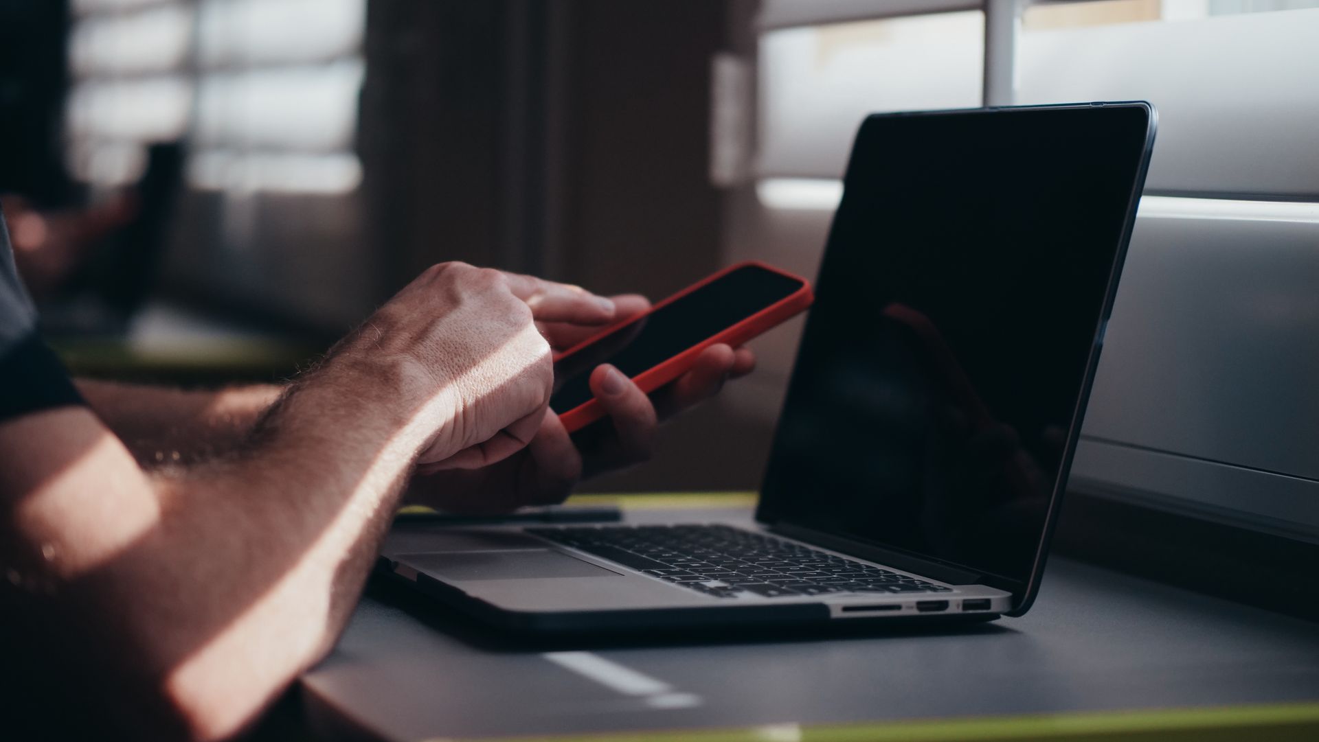 A Person Using a Cell Phone In Front of a Laptop