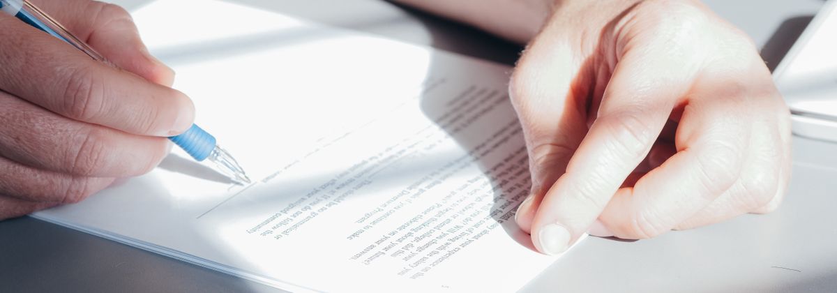 A hand signing a financial document