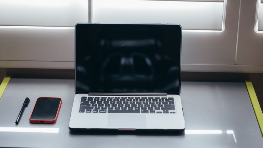 A laptop, smartphone, and pen on a desk with no people present