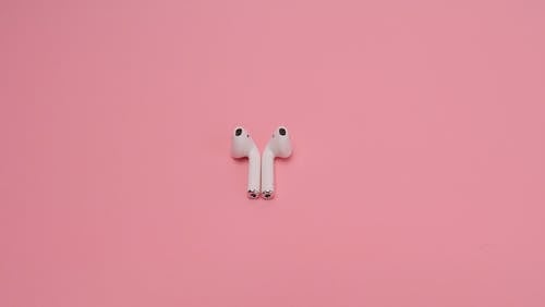 White Wireless Earphones on Pink Surface