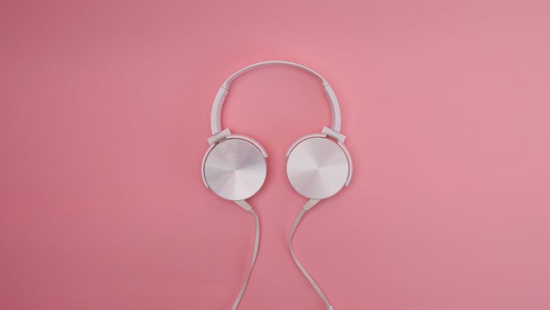 Headphone noise cancelling over-ear berwarna hitam diletakkan di atas meja kerja