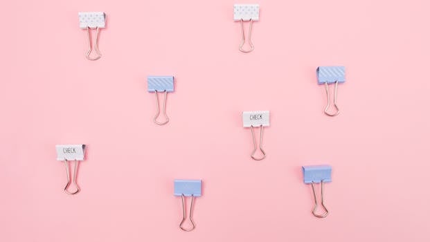 Colorful binder clips on a flat pink background create a vibrant office setup.