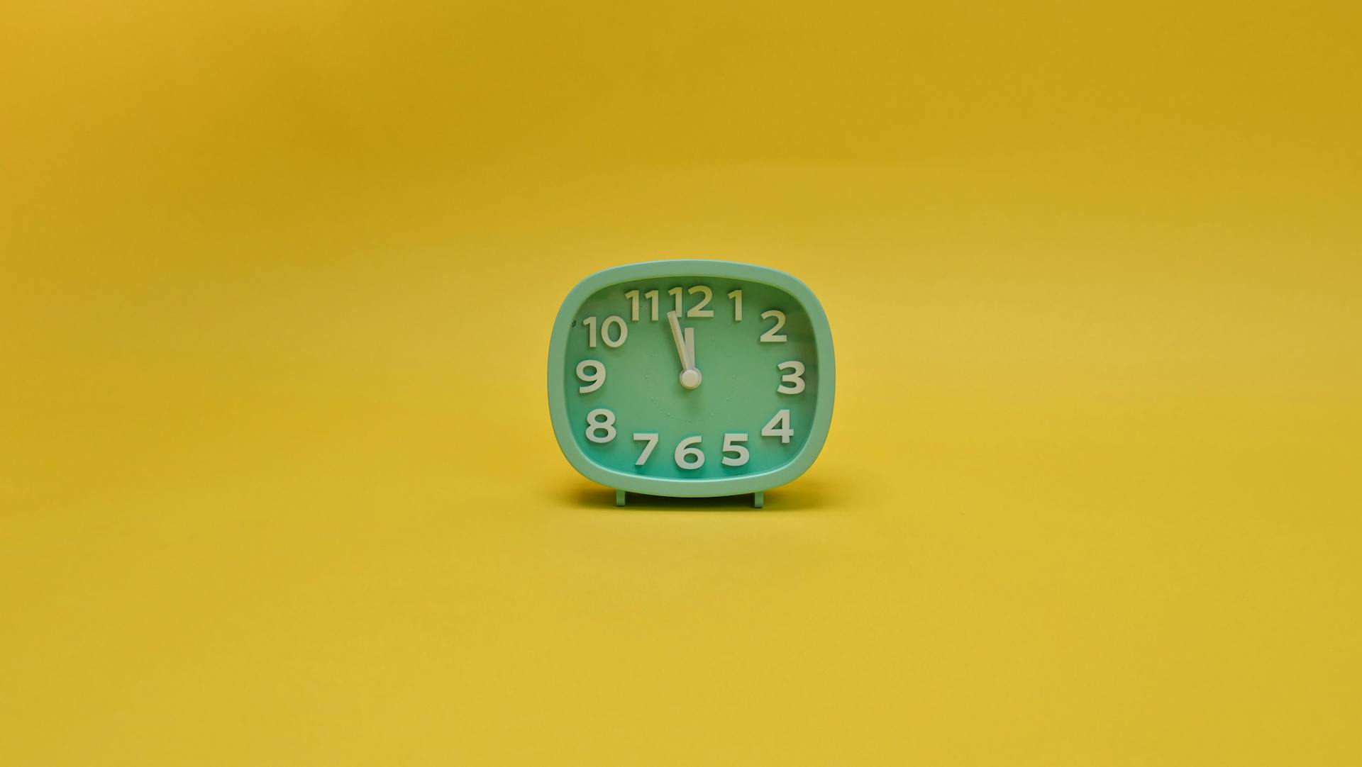 A vintage-style analog clock on a bright yellow background emphasizes time and simplicity.