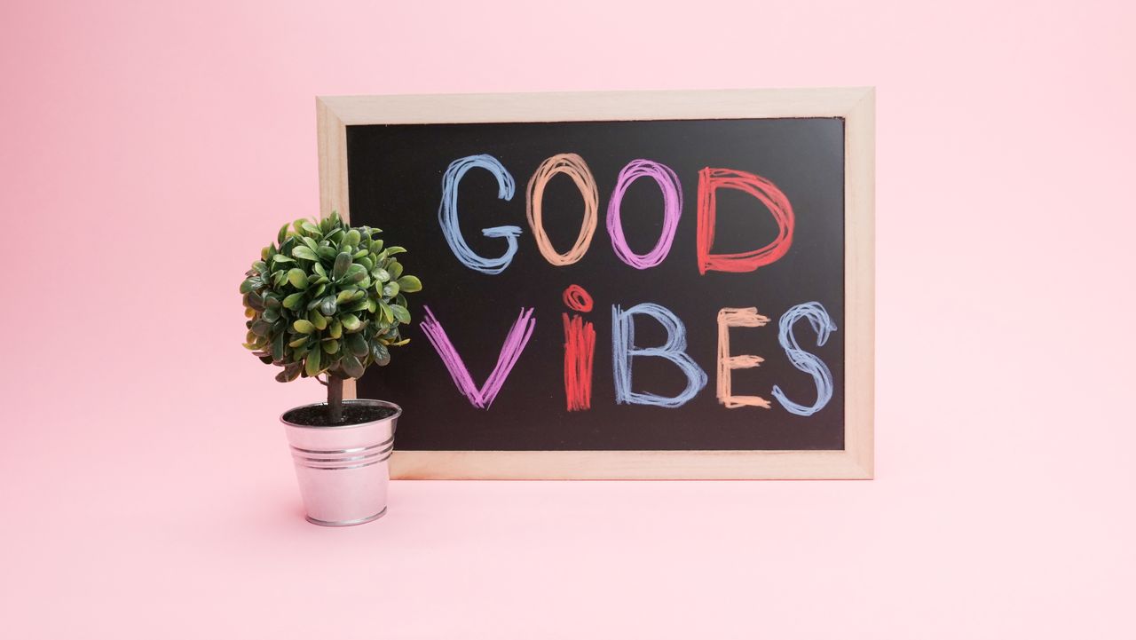chalkboard with good vibes in colorful letters against a pink backgrou