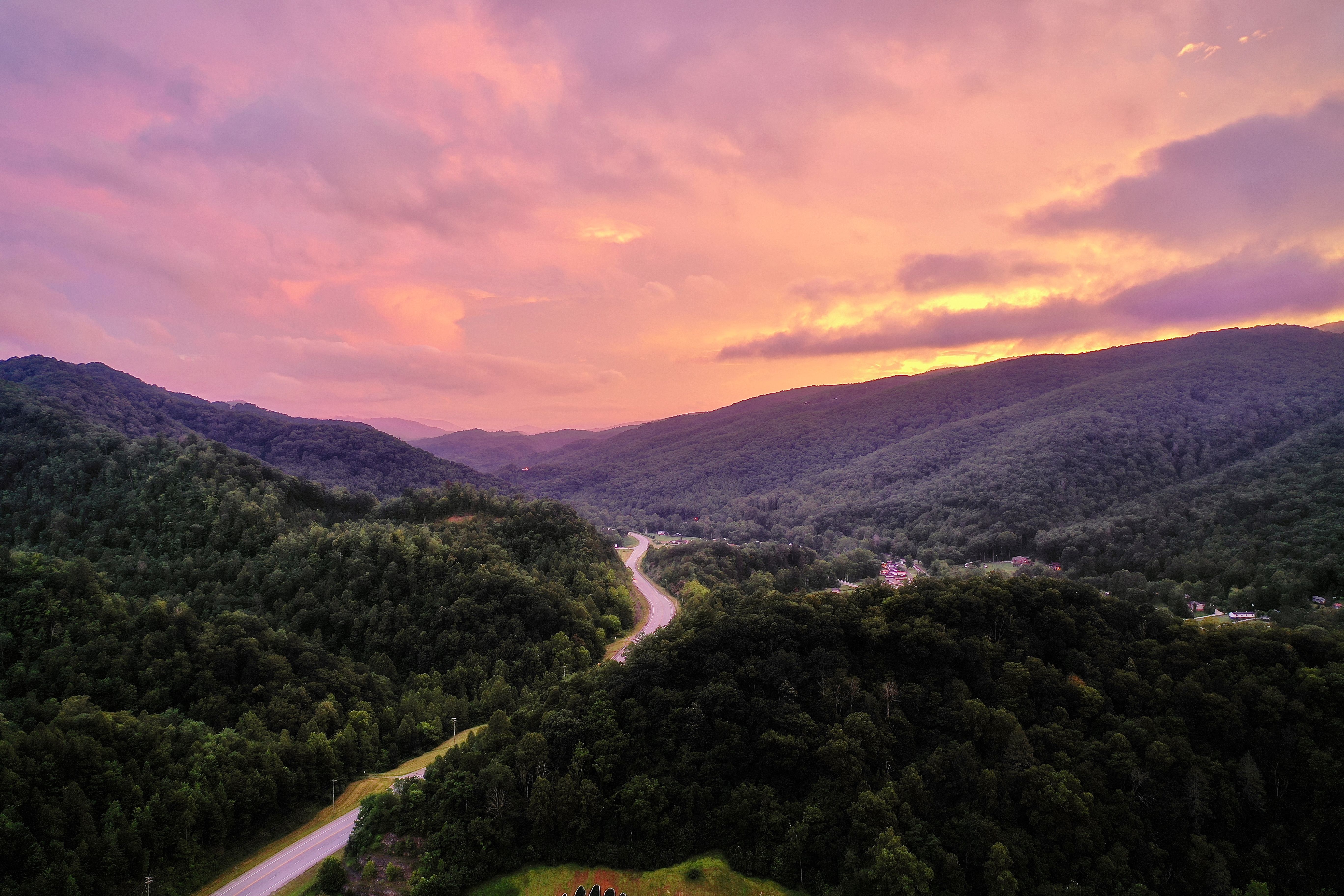 A breathtaking aerial view of sunset over lush Appalachian mountains and winding road in Harlan, KY.