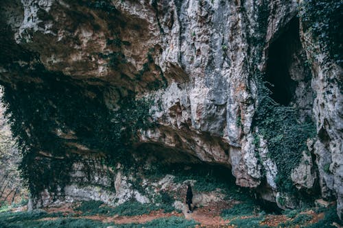 Free A lone adventurer stands before a limestone cave in Sant'Anna D'alfaedo, Italy. Stock Photo