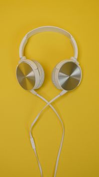 Stylish white headphones against a vibrant yellow background, perfect for music lovers.