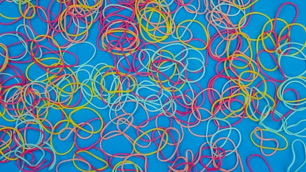 A vibrant collection of multicolored rubber bands scattered on a bright blue background.