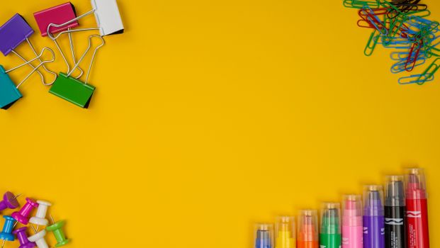 Arrangement of office supplies on a bright yellow background with ample copy space.