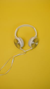 Close-up of modern headphones on a bright yellow surface offering copy space.