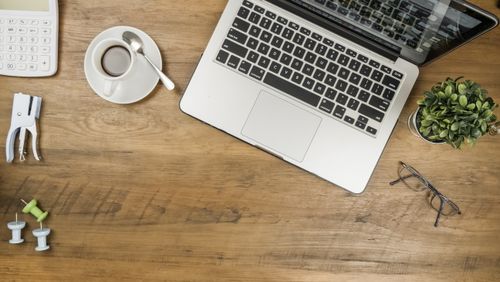 Free A flat lay of a tidy wooden desk with a laptop, coffee, and office supplies. Stock Photo