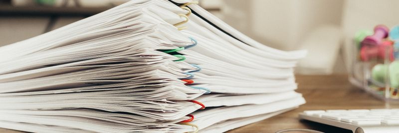 Close-up of a stack of office papers on a desk with glasses, emphasizing organization.