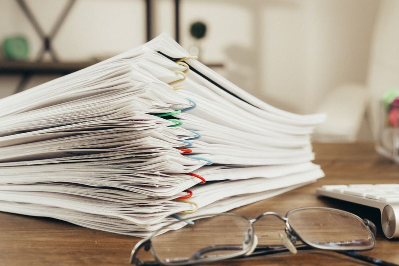 Close-up of a stack of office papers on a desk with glasses, emphasizing organization.