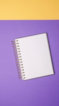 Top view of a spiral notebook on a vibrant purple and yellow background, perfect for design presentations.