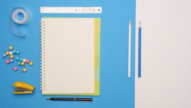 A stylish arrangement of colorful office supplies including a notepad and pencils on a blue background.