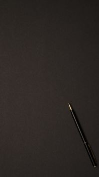 Sleek black pen on a dark background, offering ample copyspace for design purposes.