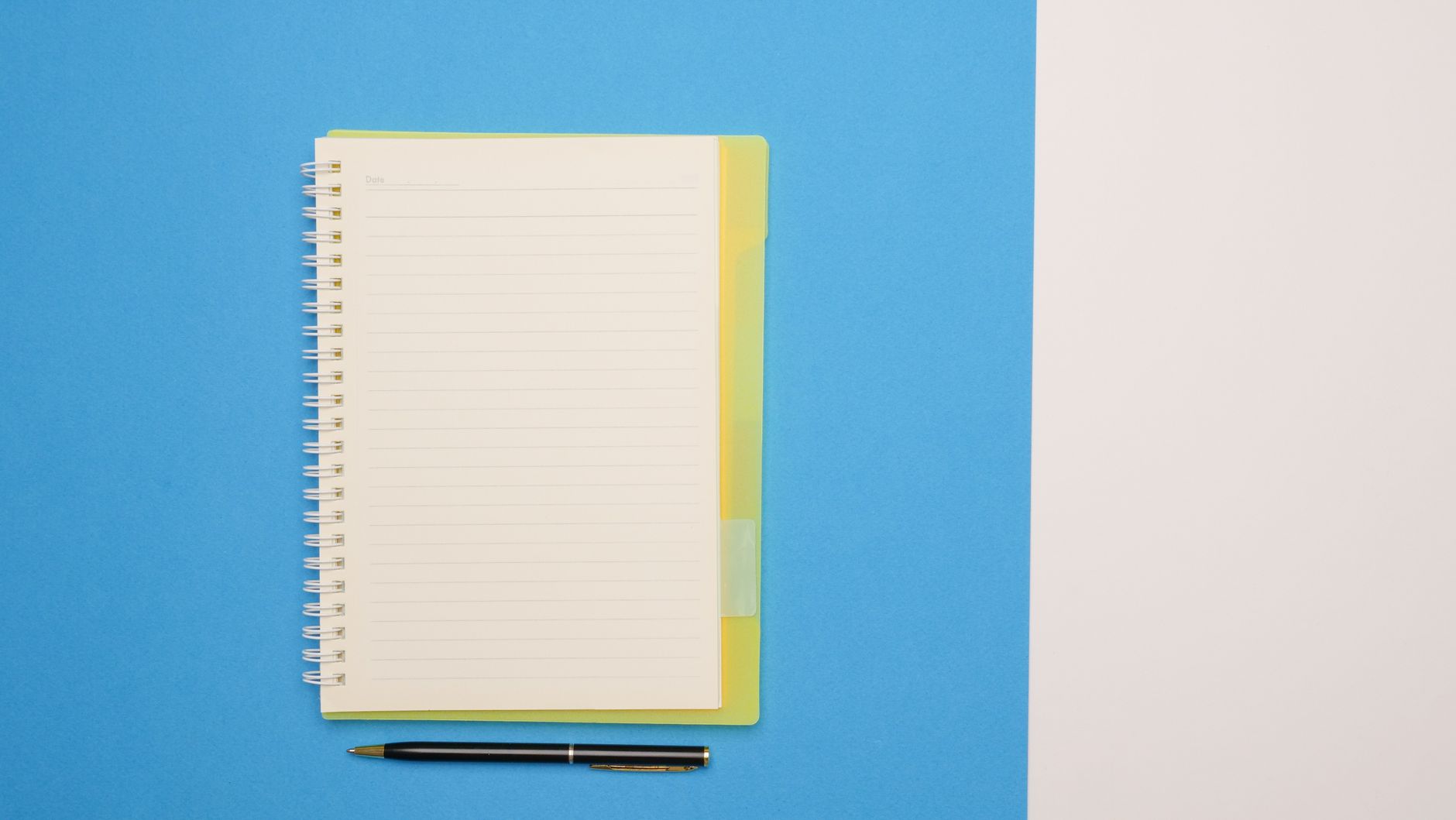 Top view of a spiral notebook and pen on a blue and white surface, ideal for mockups.