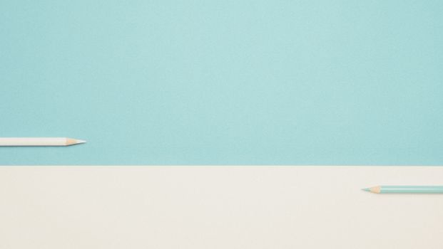 Two colored pencils on a minimalist blue and white background, perfect for design mockups.
