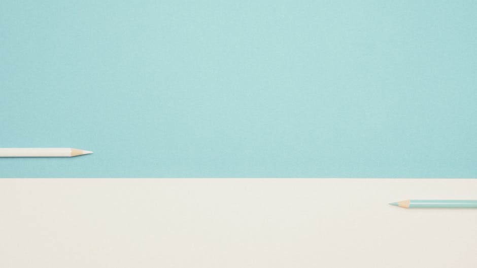 Two colored pencils on a minimalist blue and white background, perfect for design mockups.