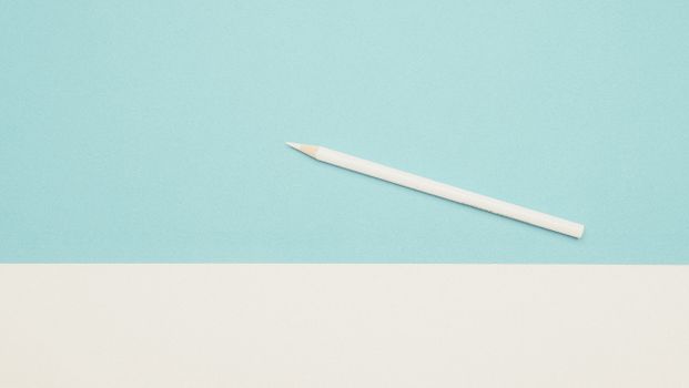 A simple white pencil placed on a blue and white minimalist background, conveying creativity and simplicity.