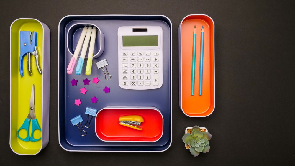 Desk trays organised with calculator, pens and supplies