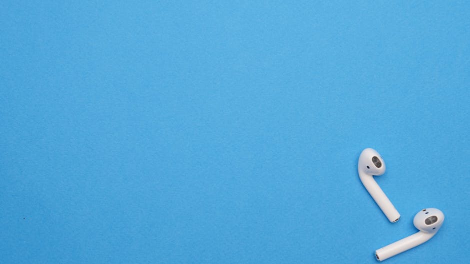 White wireless earbuds on a blue background offering ample copy space. Modern and minimalist design.