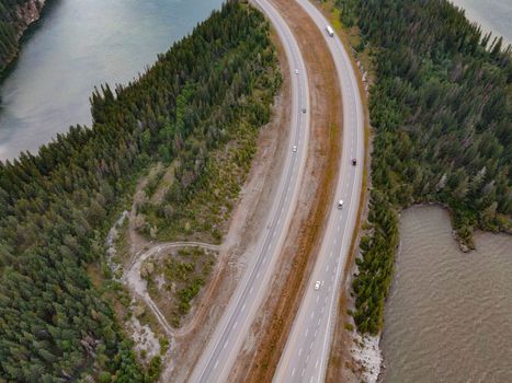 Breathtaking drone shot of a winding road surrounded by dense forest and serene waterways, perfect for wallpapers.