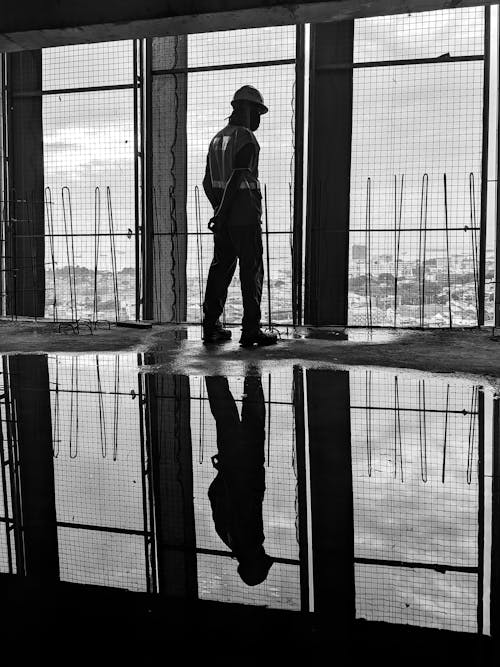 A Man Wearing Safety Work Clothes Standing Near an Open Window