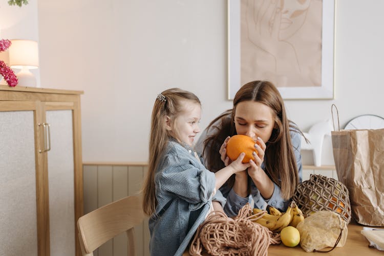 Photo Of A Mother Smelling An Orange Fruit